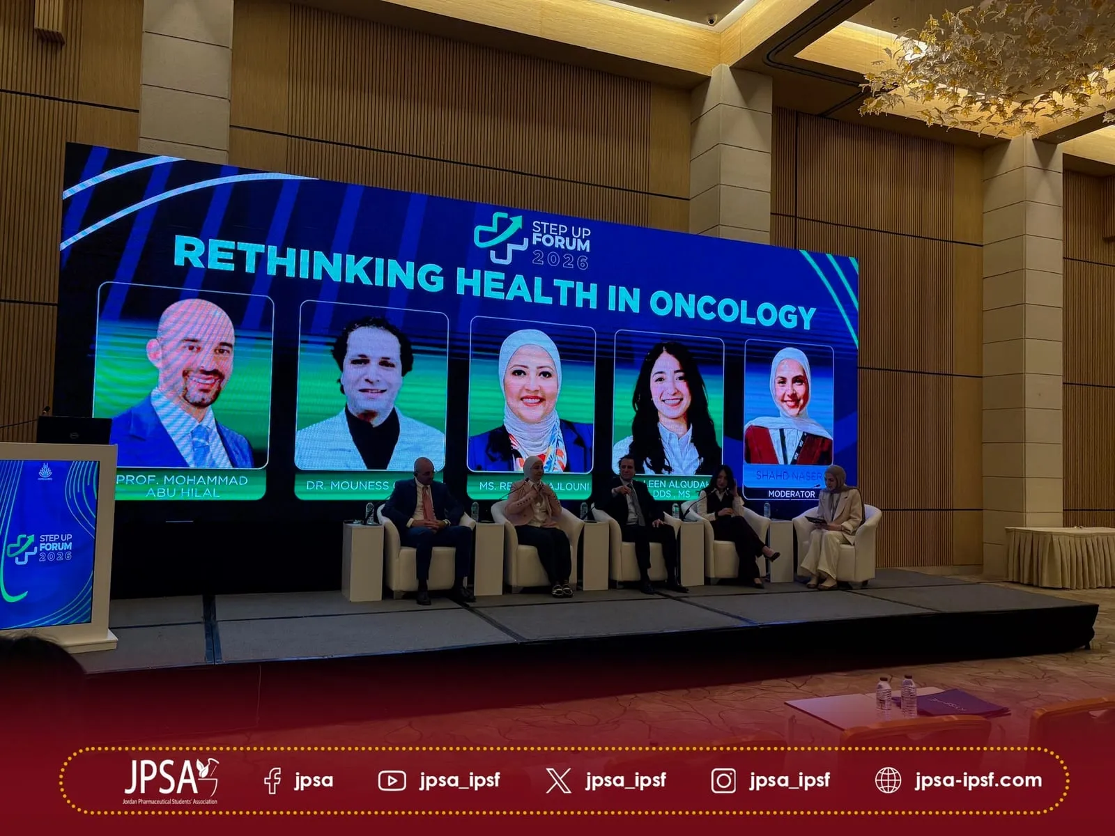 A panel seated on stage under a screen reading Rethinking Health in Oncology