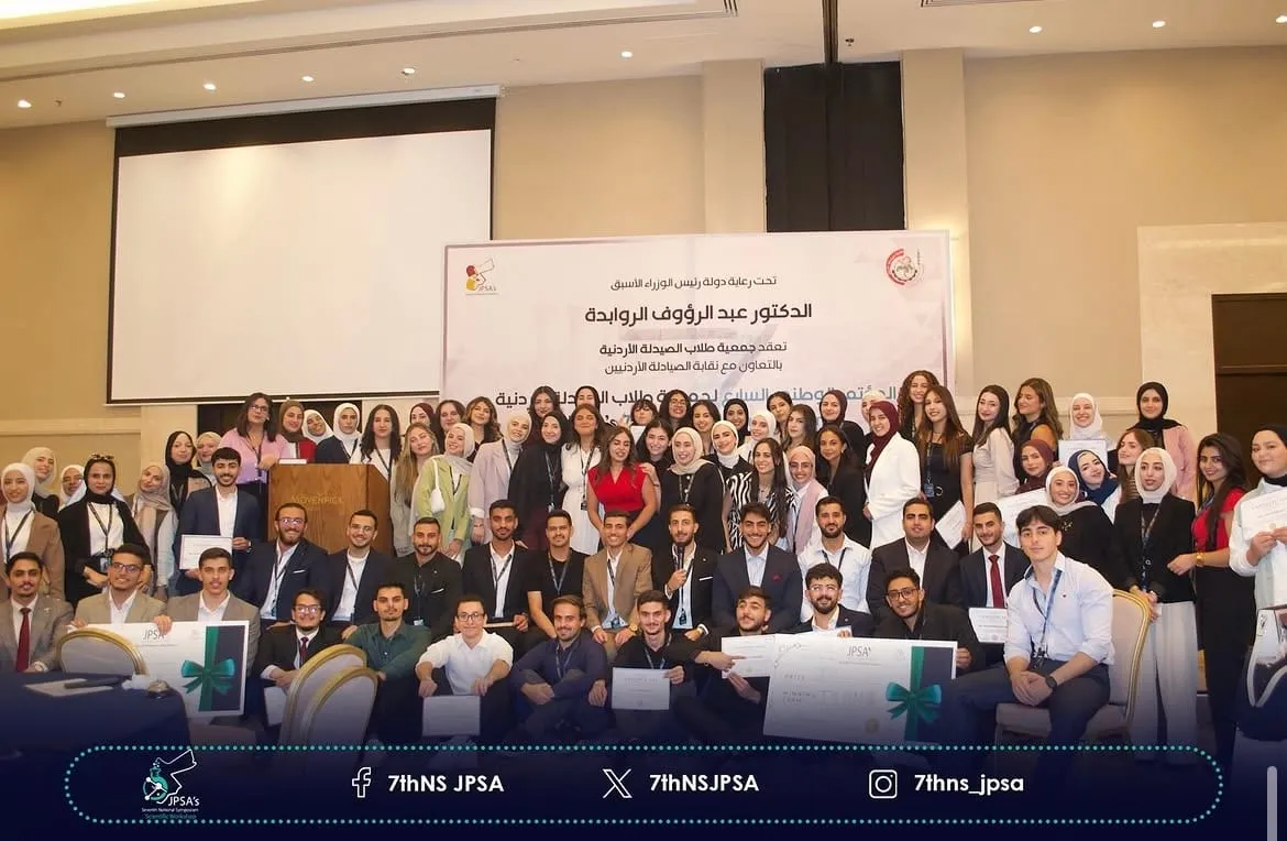 A large group photo in front of the symposium backdrop