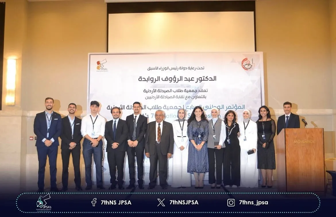 A row of people standing in front of the symposium backdrop