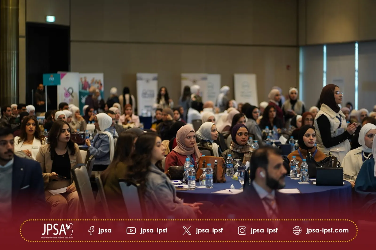 A crowded hall of attendees at round tables