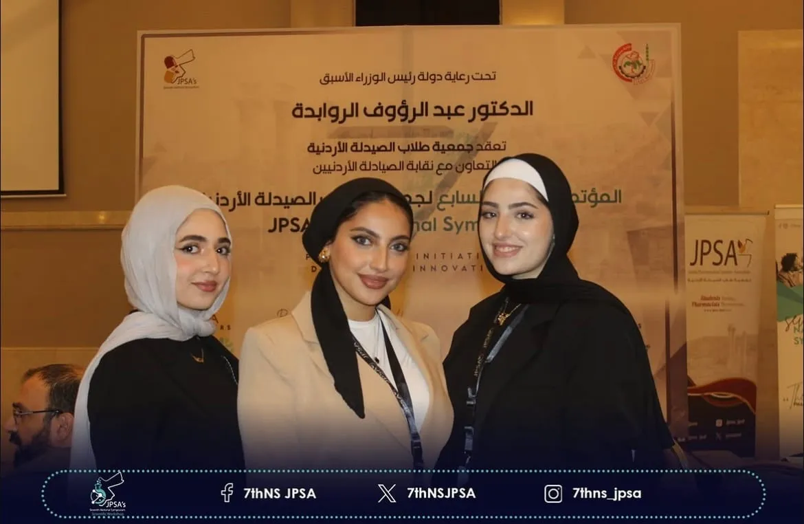 Three people posing in front of the symposium backdrop