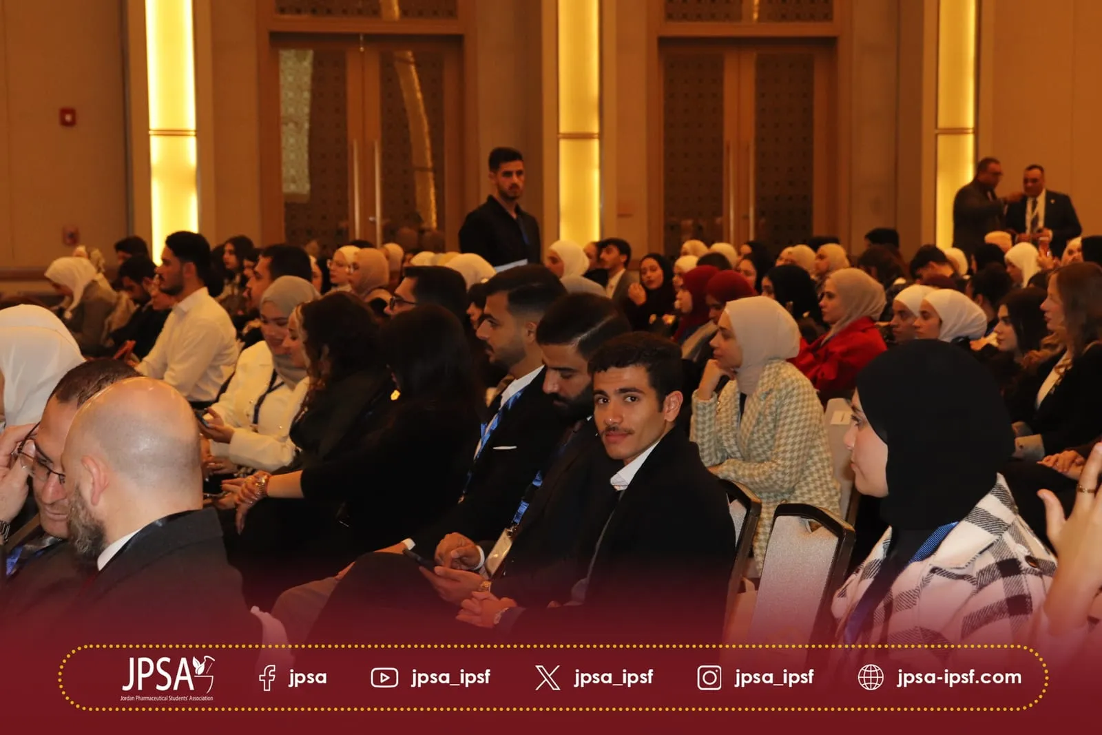 Attendees listening from their seats in a warmly lit hall