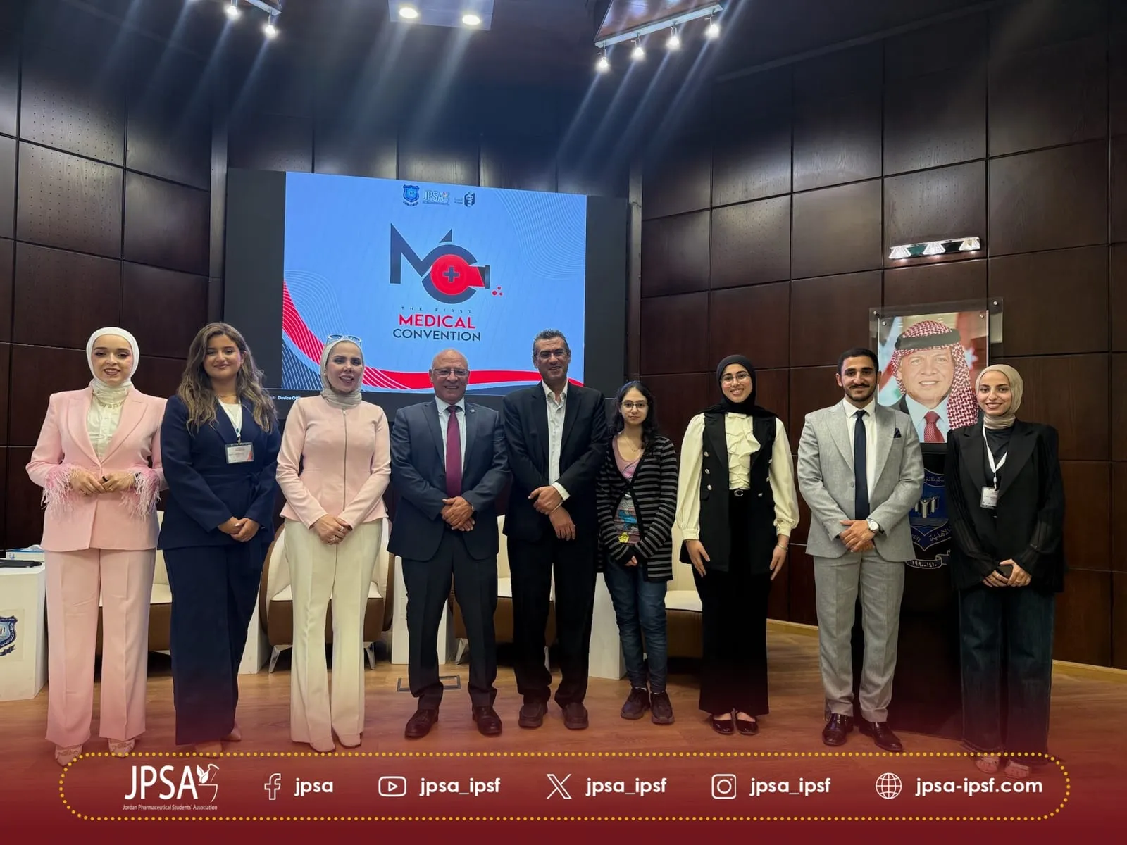 A group photo on stage, in front of a screen showing the Medical Convention logo