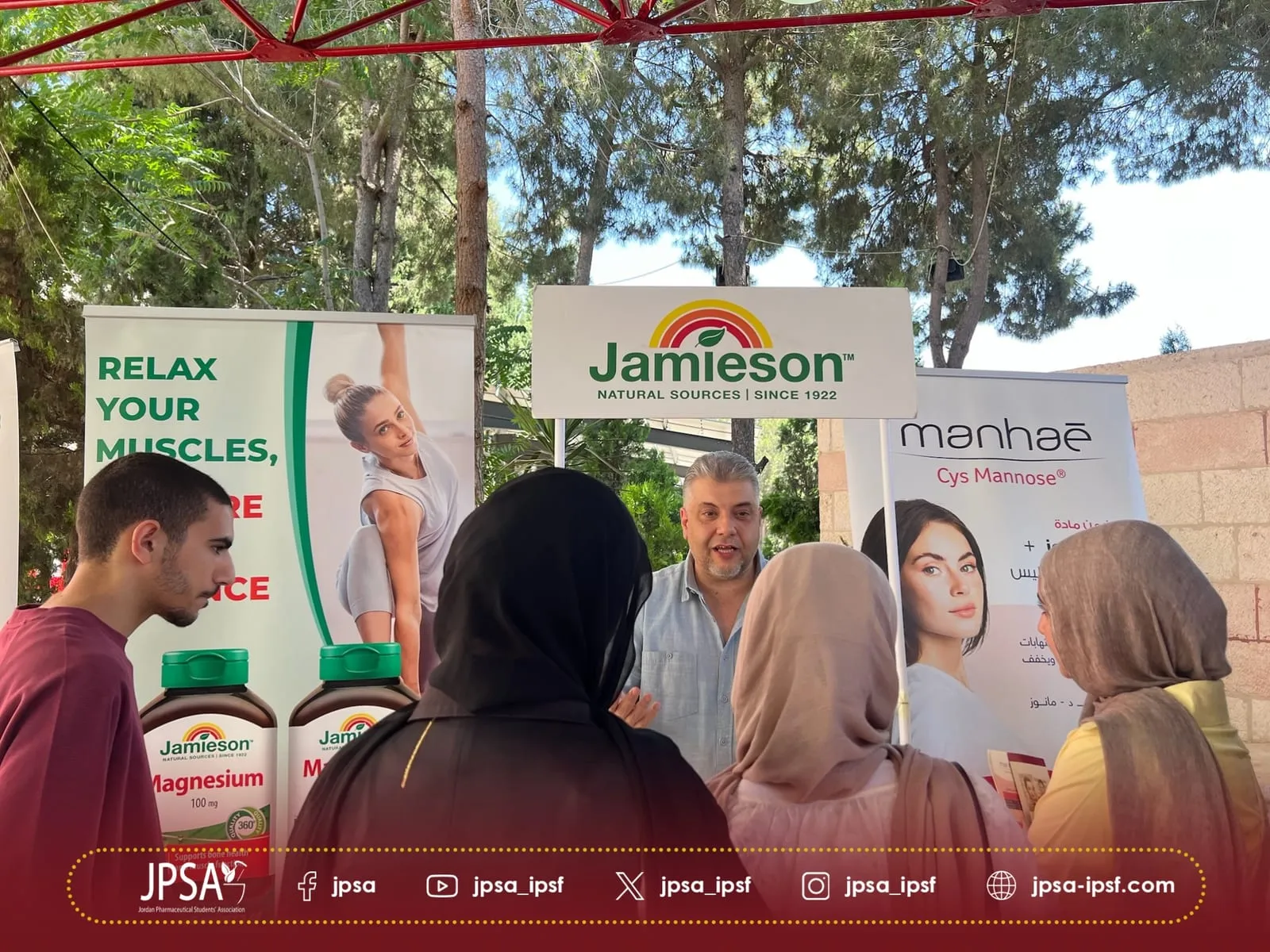 Visitors talking at a supplements stand outdoors