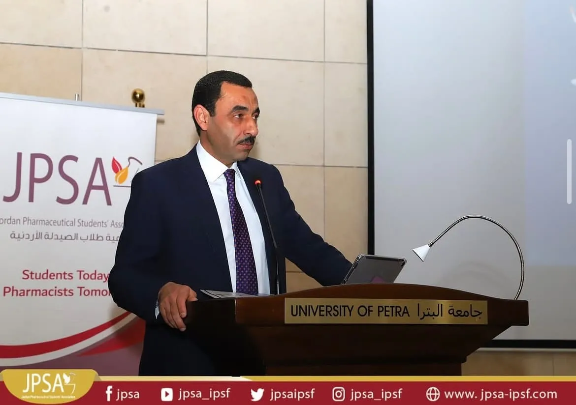 A speaker at a lectern, beside a JPSA banner
